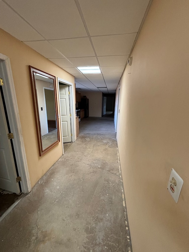 corridor featuring a drop ceiling and unfinished concrete flooring