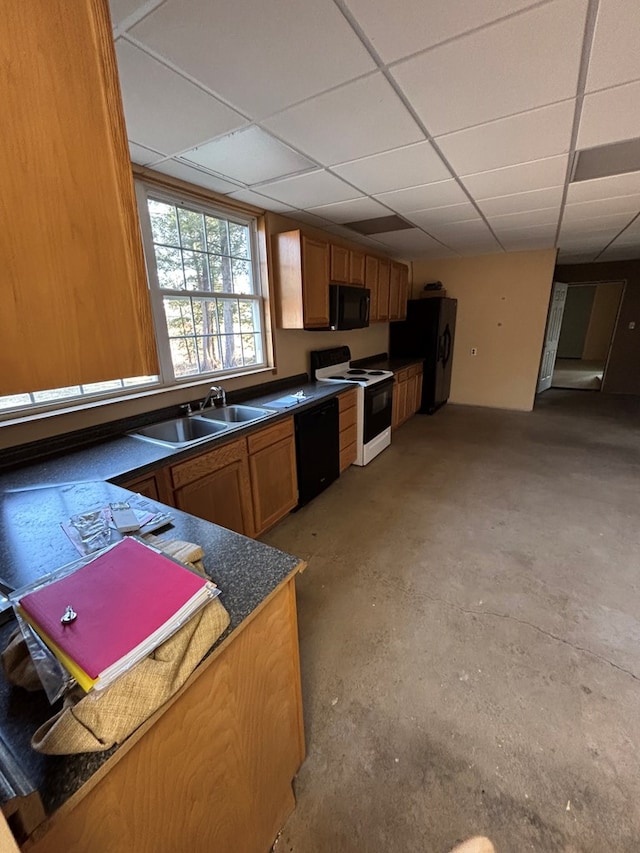 kitchen with dark countertops, a drop ceiling, black appliances, and a sink