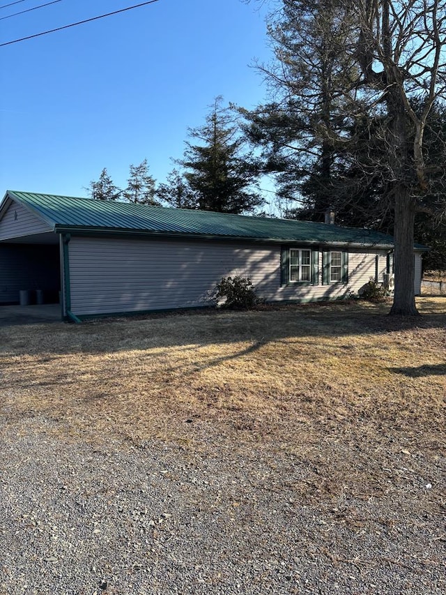 view of property exterior with an attached carport, a yard, and metal roof