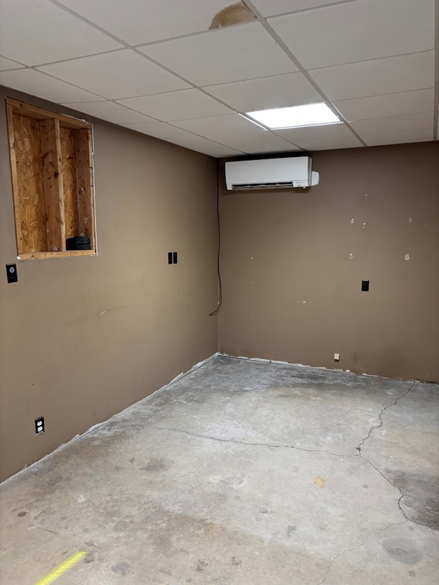 finished basement with a paneled ceiling and a wall mounted AC