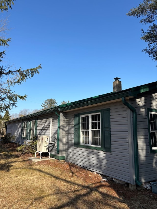 view of side of home with a chimney and a yard