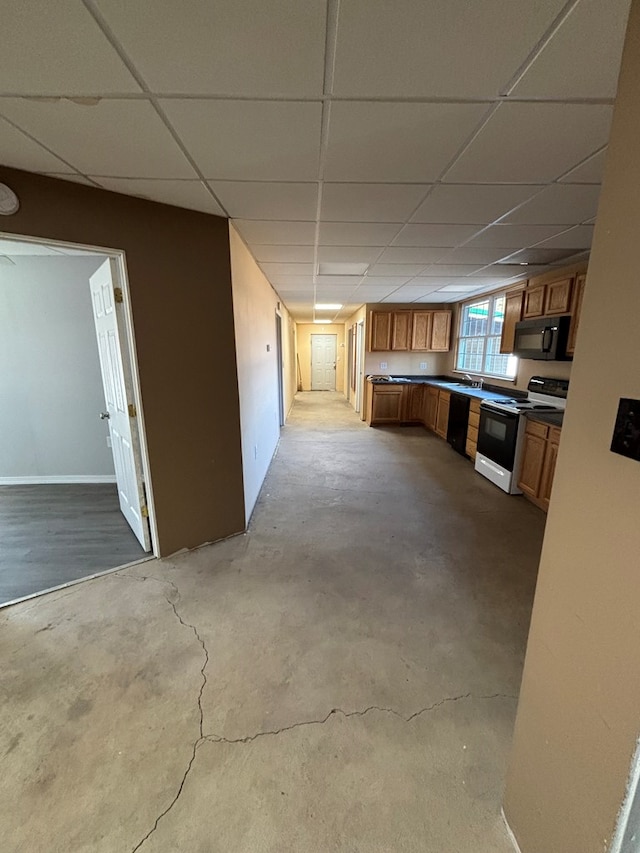 kitchen featuring unfinished concrete floors, black microwave, a drop ceiling, brown cabinets, and range with electric stovetop