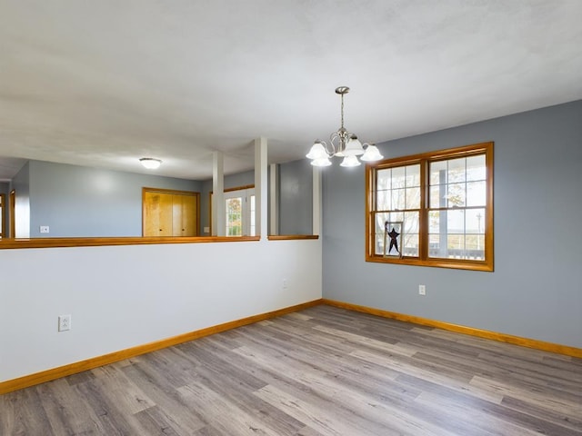 empty room with light hardwood / wood-style floors and a notable chandelier