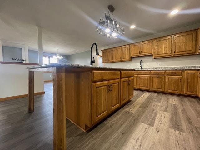 kitchen featuring pendant lighting, a center island, wood-type flooring, and an inviting chandelier