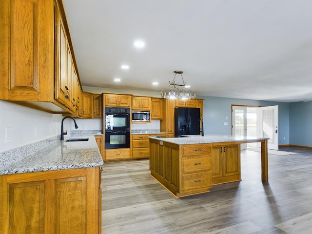 kitchen with sink, pendant lighting, a center island, and black appliances