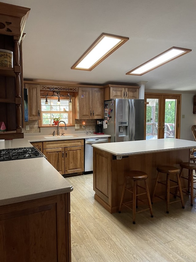 kitchen with a kitchen bar, french doors, light wood-type flooring, stainless steel appliances, and sink