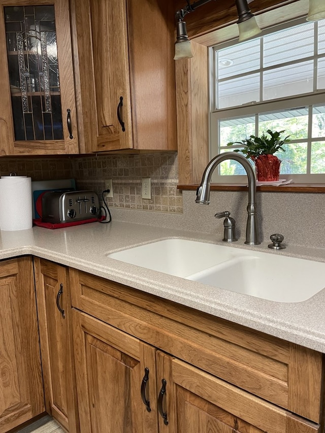 kitchen featuring decorative backsplash, light stone countertops, and sink