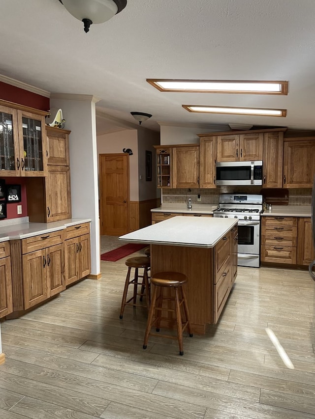 kitchen featuring a center island, a kitchen breakfast bar, crown molding, light hardwood / wood-style flooring, and stainless steel appliances