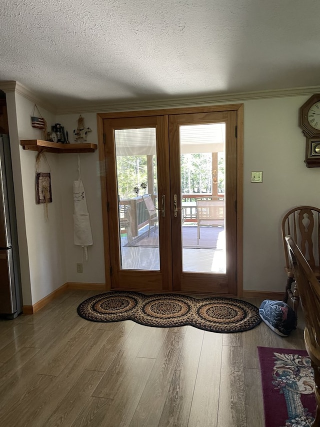 entryway featuring french doors, wood-type flooring, a textured ceiling, and ornamental molding