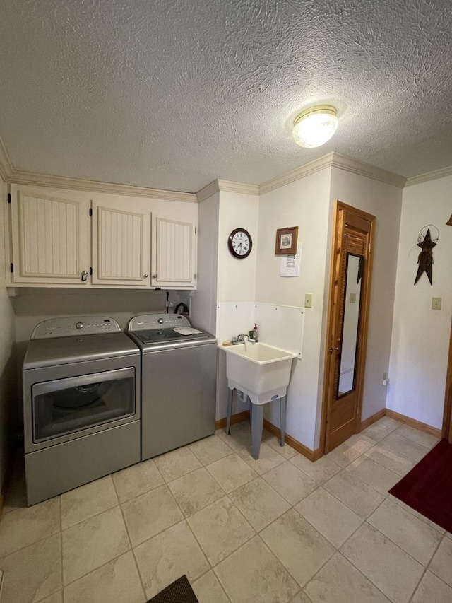 washroom with cabinets, ornamental molding, a textured ceiling, washing machine and dryer, and light tile patterned flooring