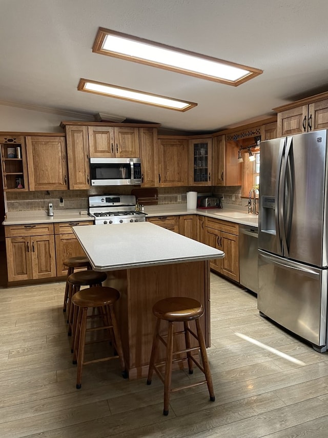 kitchen with a kitchen island, a kitchen bar, light hardwood / wood-style floors, and stainless steel appliances