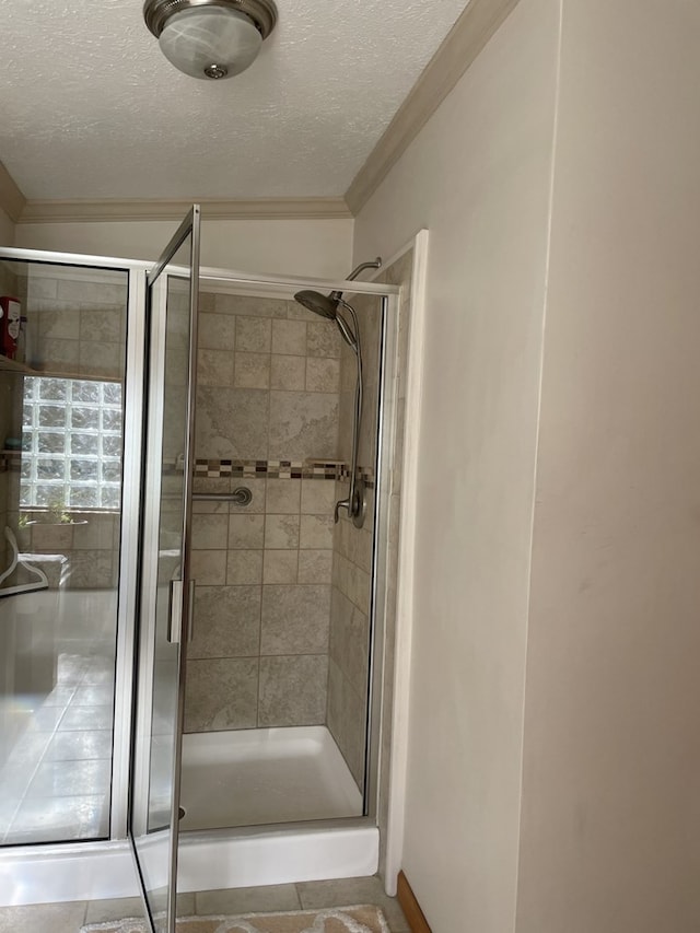 bathroom featuring a shower with shower door, a textured ceiling, and ornamental molding