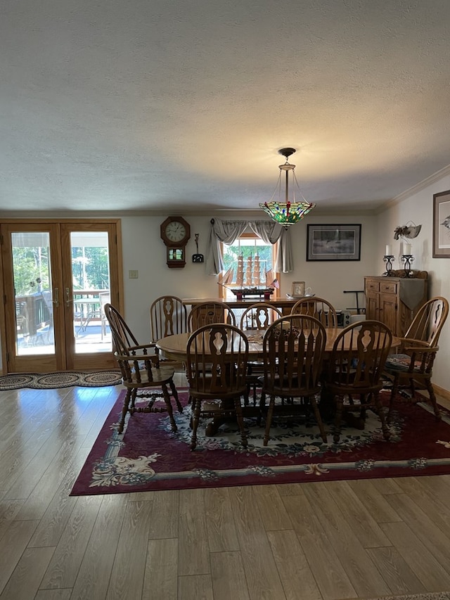 dining area featuring hardwood / wood-style floors, a textured ceiling, french doors, and crown molding