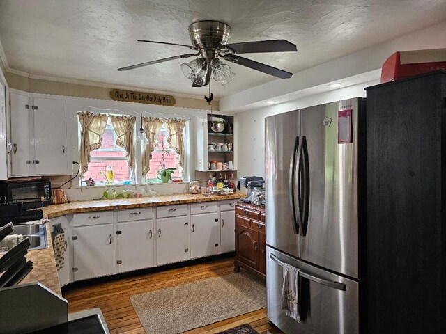 409 E Main St, Elkland, PA 16920 - kitchen with freestanding refrigerator, light countertops, white cabinetry, a ceiling fan, and wood finished floors