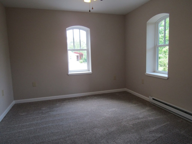 empty room with ceiling fan, dark carpet, and baseboard heating