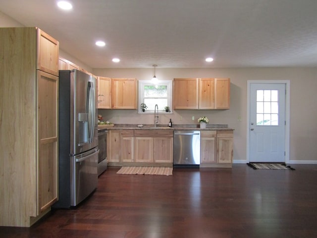 kitchen featuring stainless steel appliances, sink, light brown cabinetry, and decorative light fixtures