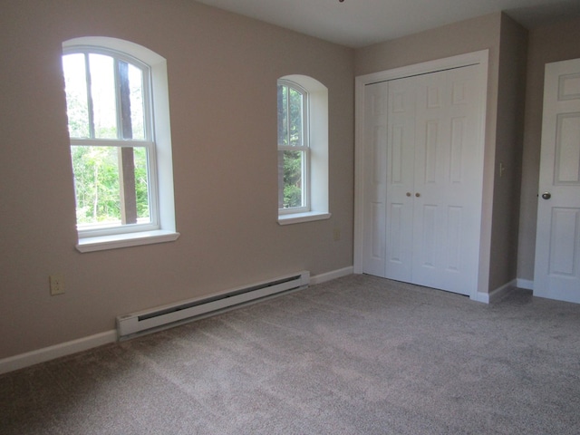 unfurnished bedroom with baseboard heating, light carpet, and a closet