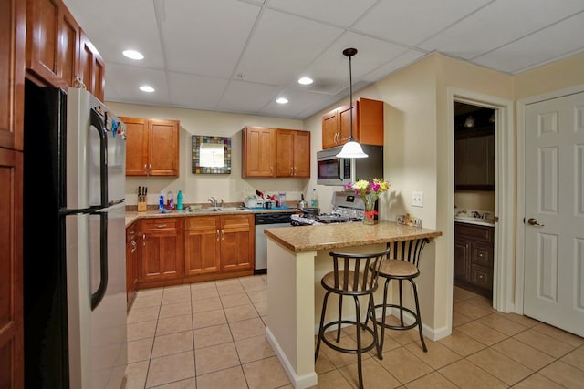 kitchen with a breakfast bar, pendant lighting, stainless steel appliances, kitchen peninsula, and light stone countertops