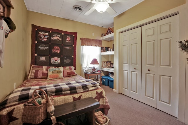 carpeted bedroom with ornamental molding, a closet, and ceiling fan