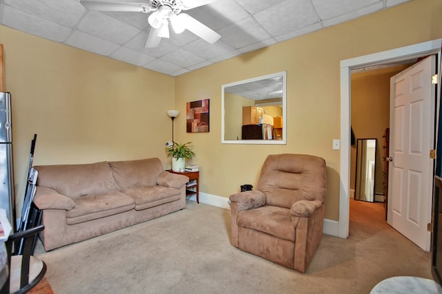 carpeted living room featuring ceiling fan and a paneled ceiling