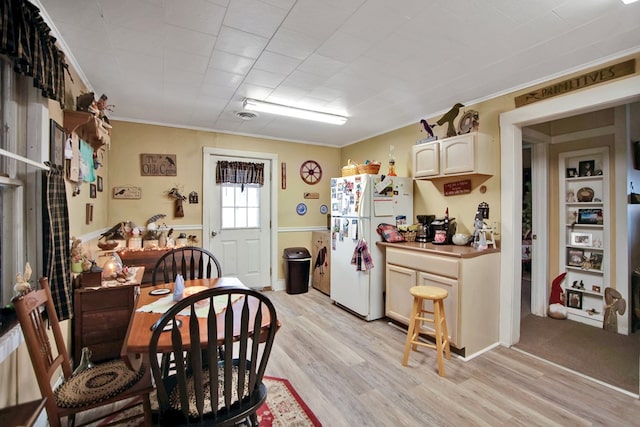 dining space with light wood-type flooring and crown molding