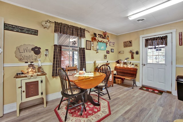 dining space featuring light hardwood / wood-style floors, plenty of natural light, and ornamental molding