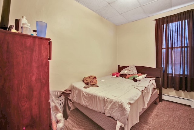 bedroom with a paneled ceiling, carpet flooring, and a baseboard heating unit