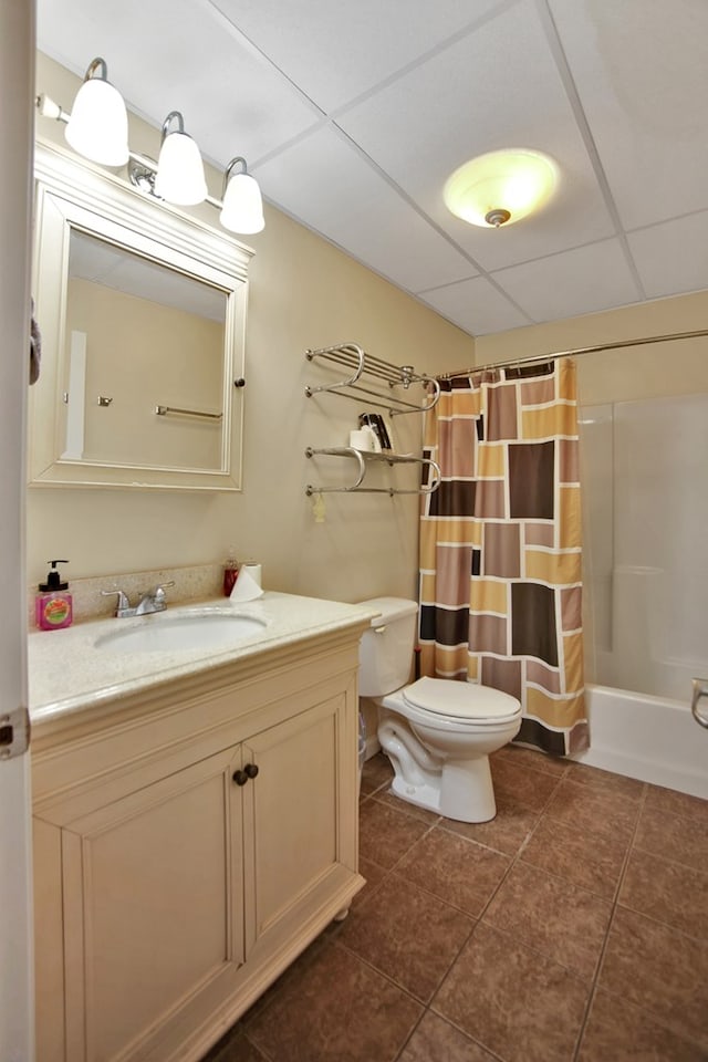 full bathroom featuring tile patterned flooring, toilet, shower / bath combo with shower curtain, a drop ceiling, and vanity