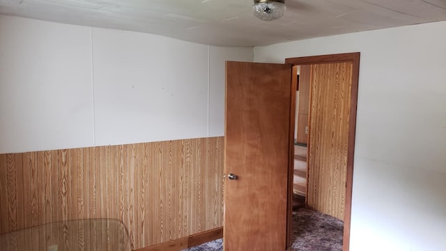 carpeted spare room featuring wooden walls