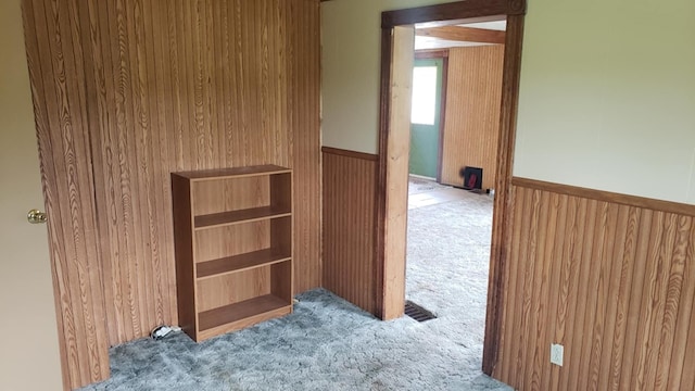 hall with wood walls and light colored carpet