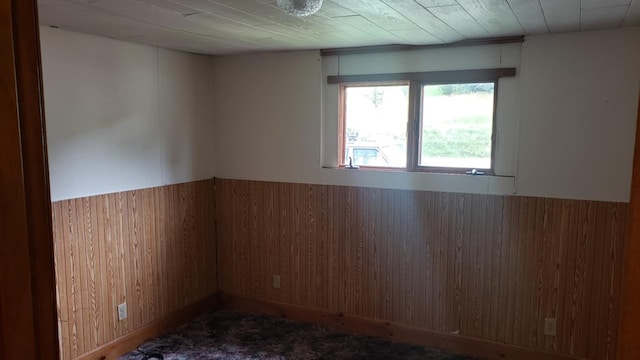 empty room featuring dark carpet and wood walls