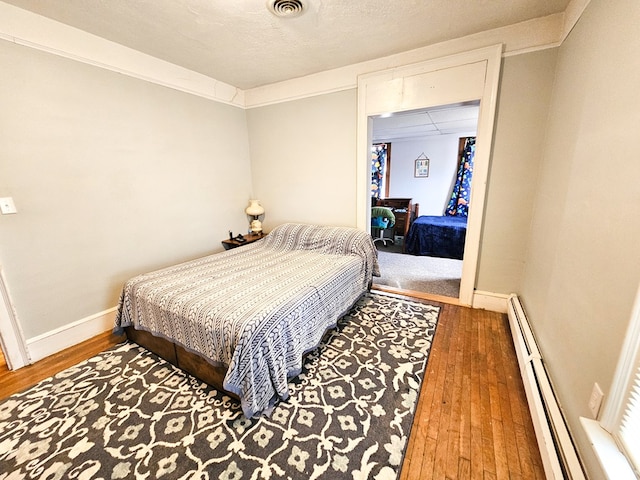 bedroom with hardwood / wood-style floors and a baseboard radiator