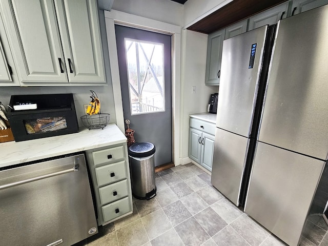 kitchen with appliances with stainless steel finishes, gray cabinets, and light stone counters