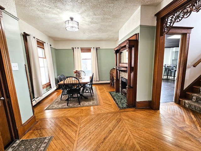 dining area featuring hardwood / wood-style floors, a textured ceiling, a fireplace, and a baseboard heating unit