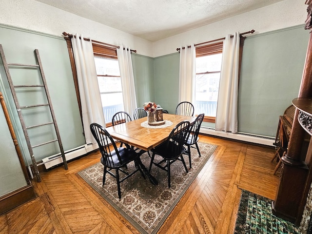 dining area with parquet flooring, a baseboard radiator, and a wealth of natural light