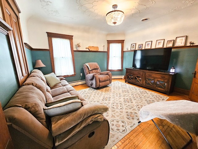 living room featuring light hardwood / wood-style flooring, a baseboard radiator, and a notable chandelier