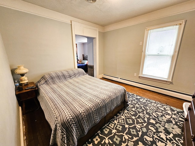 bedroom featuring an AC wall unit, hardwood / wood-style floors, a textured ceiling, and a baseboard heating unit