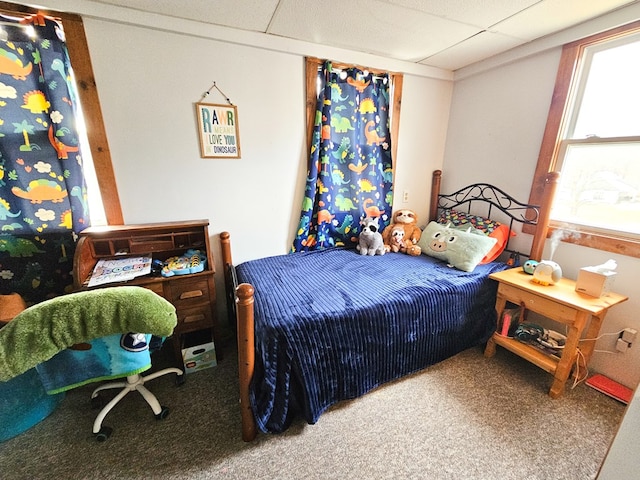 carpeted bedroom featuring a drop ceiling