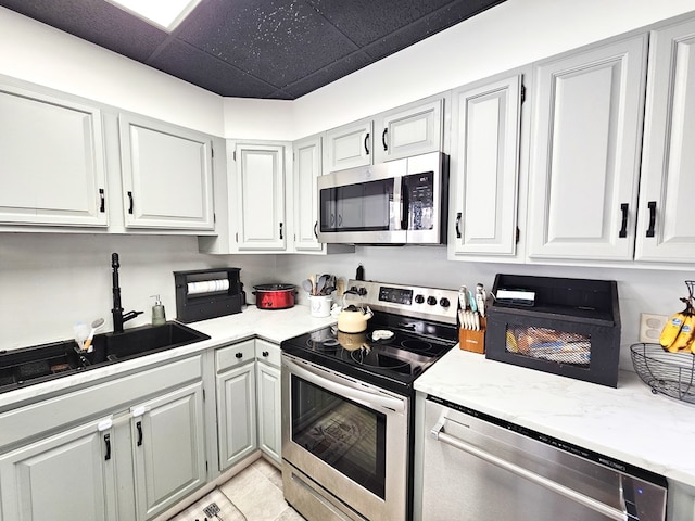 kitchen featuring light tile patterned floors, a paneled ceiling, stainless steel appliances, and sink