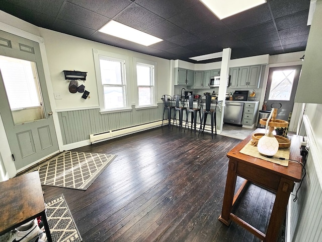 interior space featuring a paneled ceiling, dark hardwood / wood-style floors, and baseboard heating