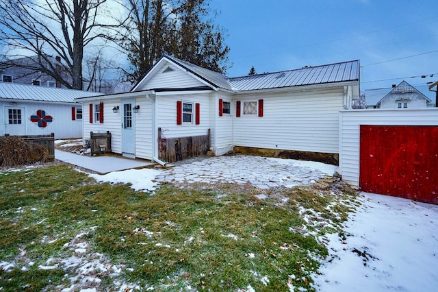 snow covered rear of property featuring a yard