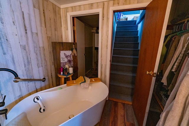 bathroom featuring sink, a tub, and wooden walls