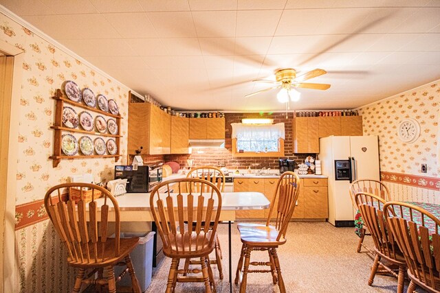 dining room with light colored carpet, ceiling fan, ornamental molding, and sink