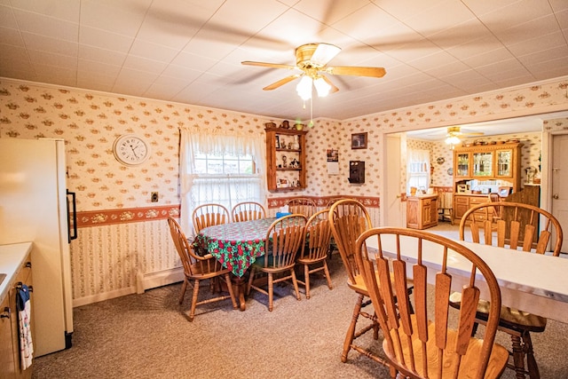 carpeted dining room featuring a baseboard heating unit, ceiling fan, and crown molding