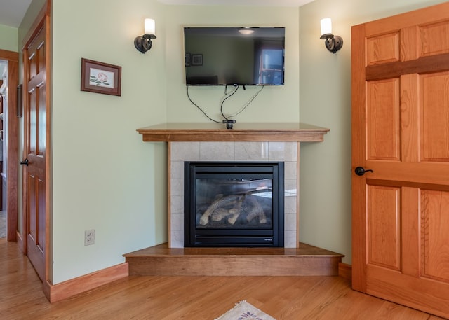 interior details with a tiled fireplace and wood-type flooring