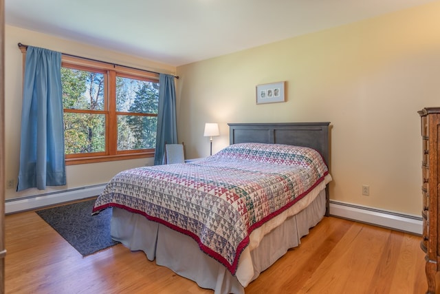 bedroom with hardwood / wood-style floors and a baseboard heating unit