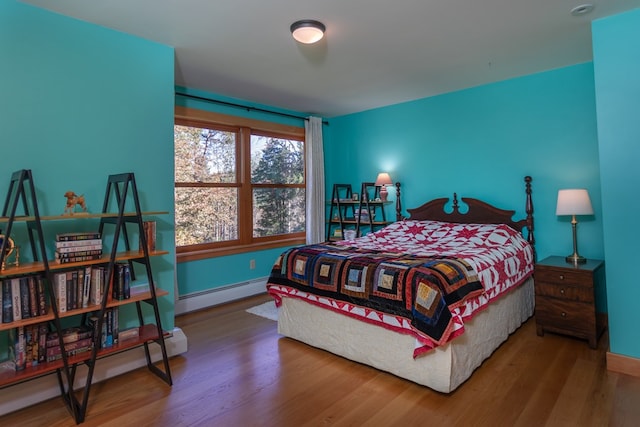 bedroom with hardwood / wood-style floors and a baseboard heating unit