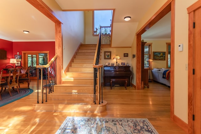 staircase with hardwood / wood-style flooring and ornamental molding