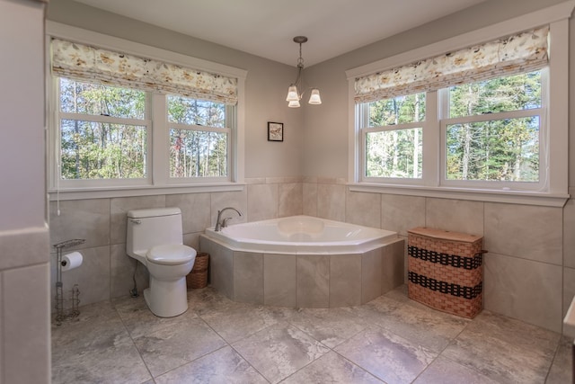 bathroom featuring tiled tub, toilet, and a notable chandelier