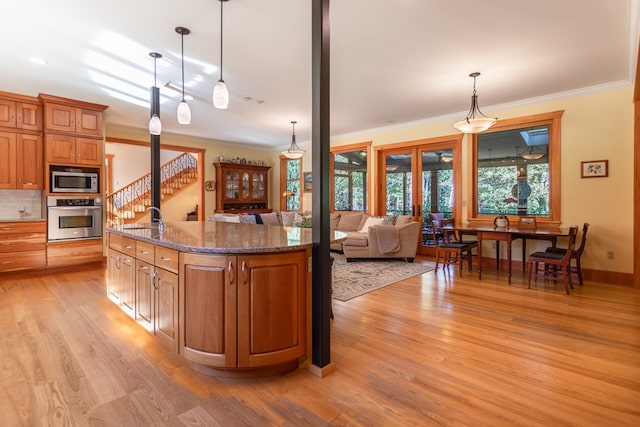 kitchen featuring decorative light fixtures, stainless steel appliances, crown molding, and sink